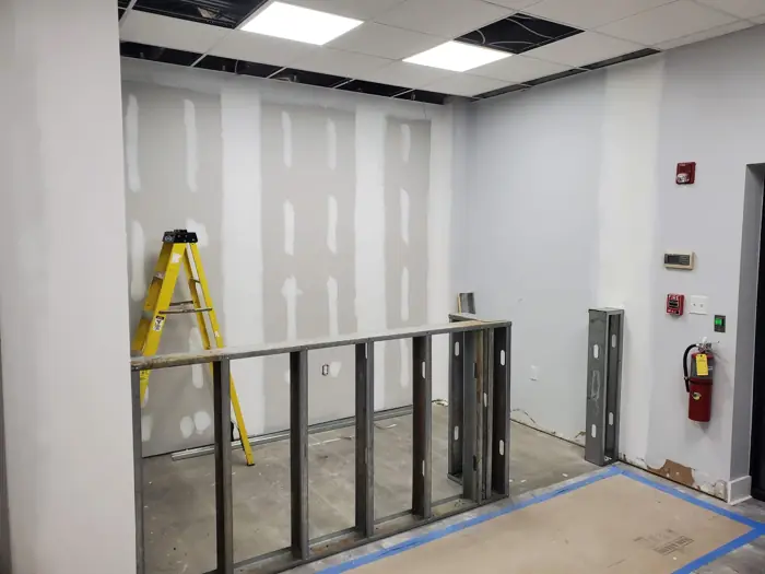 Metal stud framing with taped drywall and ceiling grid in progress