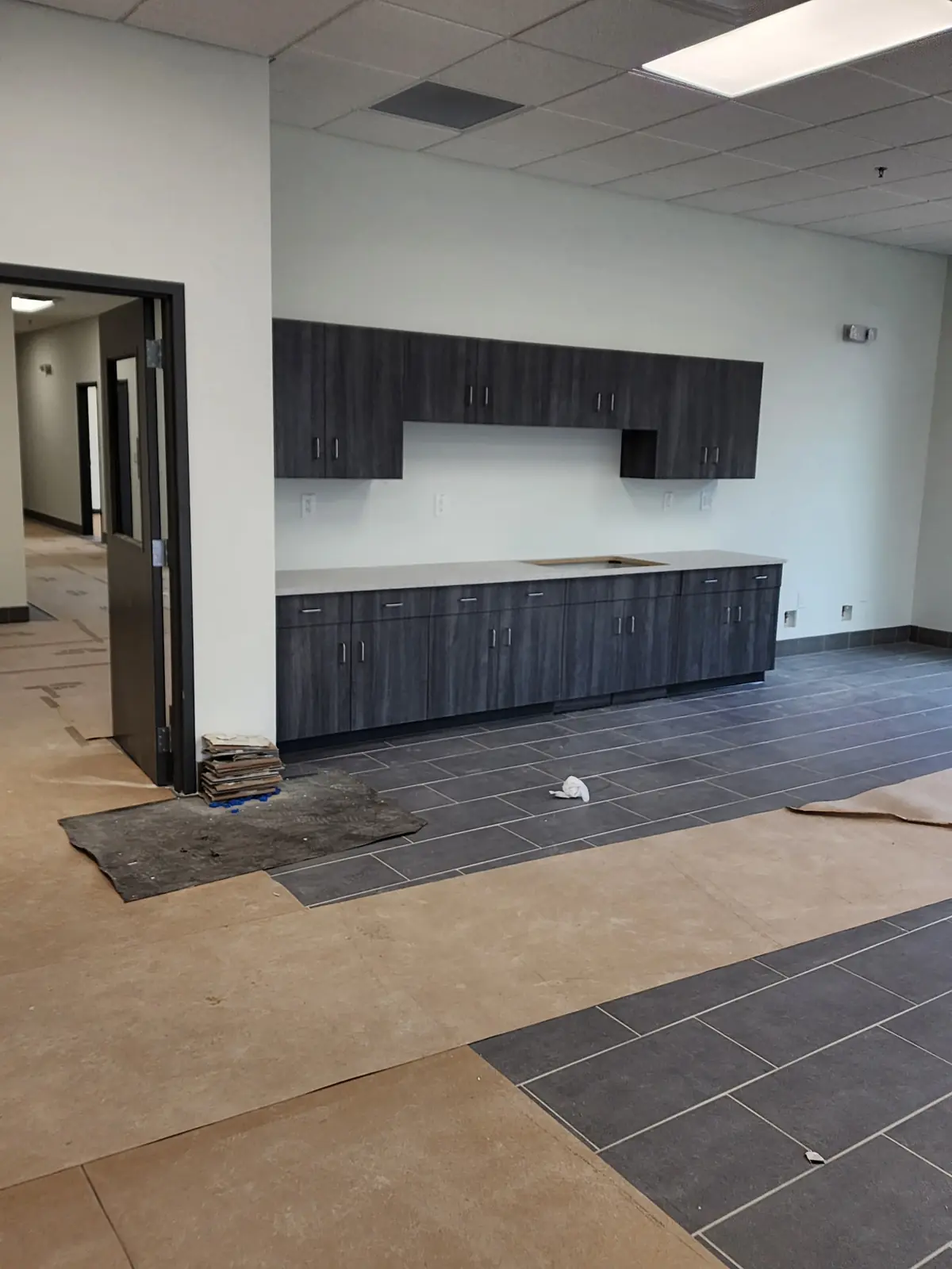 Upfitted break room with dark cabinetry and new tile flooring