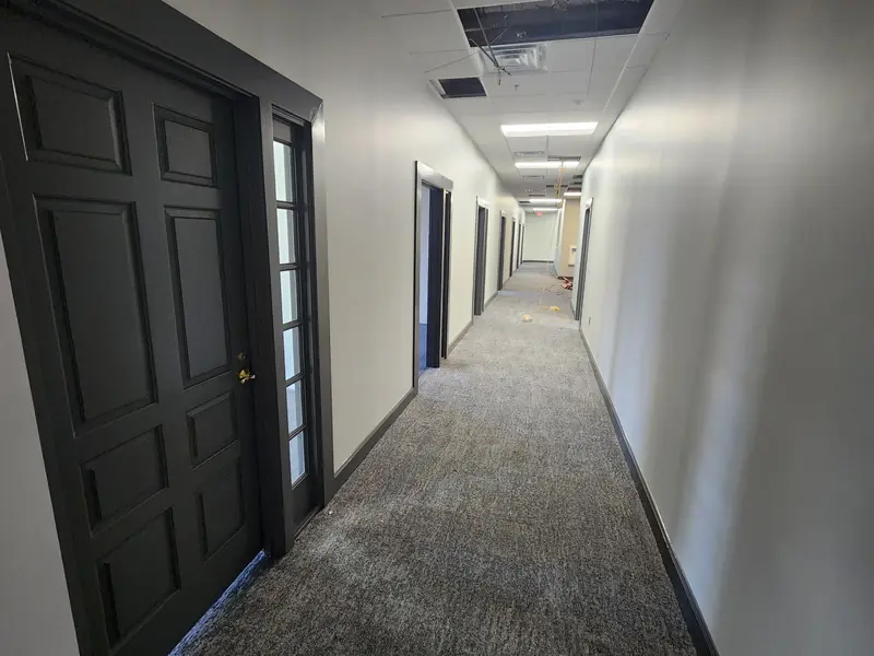 Finished carpeted corridor with dark paneled office doors